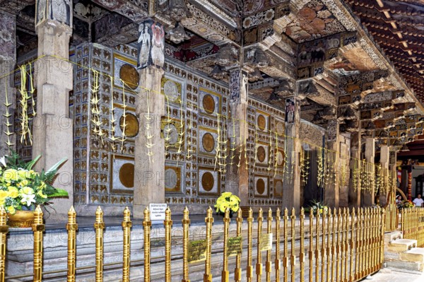 Richly decorated temple structure with ornate columns, golden ornaments and floral decorations in a