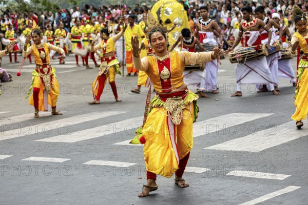 Woman in glowing traditional costume dances joyfully at a cultural parade, The Perahera Parade in