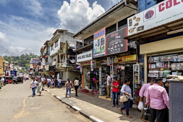 Busy shopping street with shops and passers-by under a cloudy sky in an urban setting, The shopping