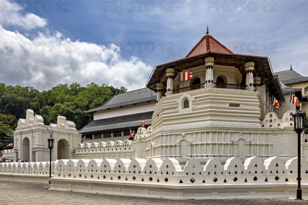 Temple complex with white wall, pavilion and colorful flags on a clear day, The Temple of the Tooth