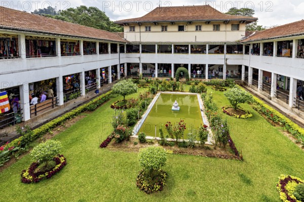 A well-kept courtyard with a central fountain and surrounding flower beds in a historic building,