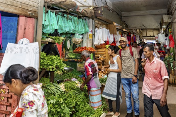 Customers and sellers in a lively vegetable stand at a market, dealers in the market halls of Kandy