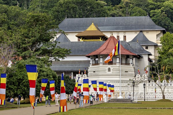 Historic building with colorful flags and group of visitors in a green setting, The Temple of the