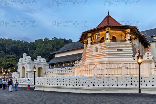 Historic building illuminated at dusk with visitors in the foreground, The Temple of the Tooth in