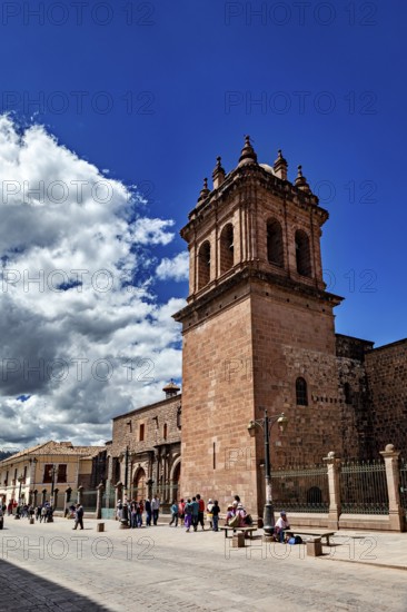 Distinctive bell tower and wall on a busy street under blue sky with clouds, The churches of Cusco