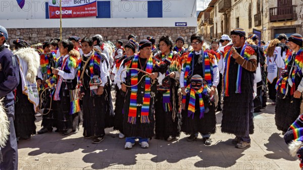 People wearing traditional clothes wearing colorful scarves take part in a street parade,