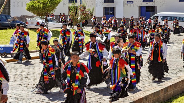 Children and adults in traditional garments move in a colorful procession on the street,