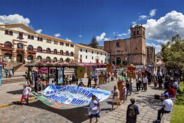 Bustling square with people and a church in the background, traditional parade of festival groups