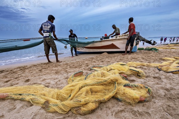 Fishermen on the beach catch up with nets, the sea is calm and the sky is cloudy, Traditional