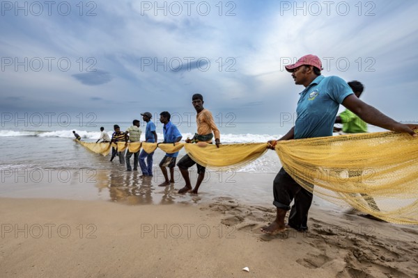 Fishing community draws a long net from the sea, focus on teamwork, traditional fishermen on