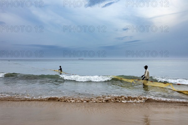 Two fishermen in the sea pull a net across the waves, calm coastal atmosphere, traditional