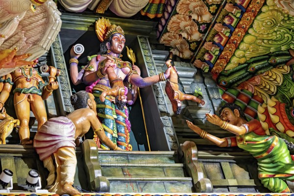 Complex sculpture scene with figures depicting rituals in traditional temple colors, The Sri