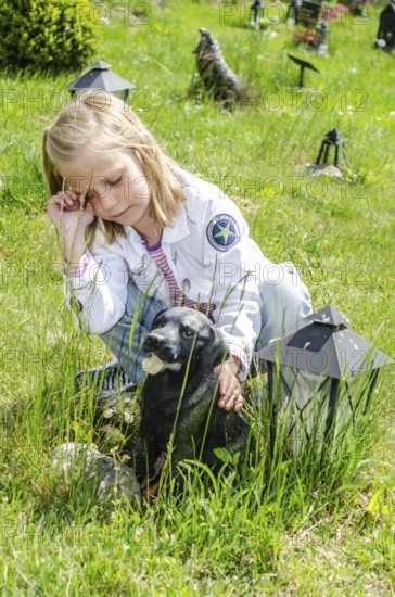 Grieving blonde 7-year-old girl at her dog's grave at pet cemetery in Ystad, Skåne County, Sweden,