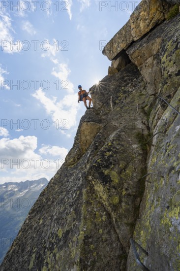 Female mountaineer on steep rock face on the secured via ferrata Krokodil-Bergsee am