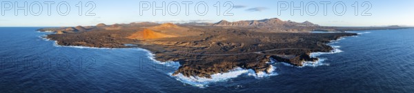 Coast with lava fields, volcanic landscape near Los Hervideros with red volcano Montaña Bermeja, in