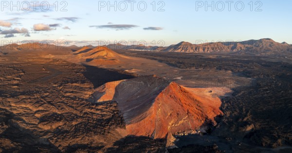 Picturesque volcanic landscape in evening light, red volcano Montaña Bermeja between lava fields,