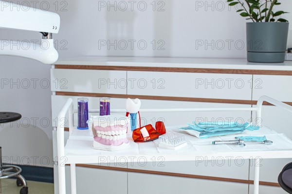 Various instruments, dental models, and hygiene items are laid out on the table in the dental