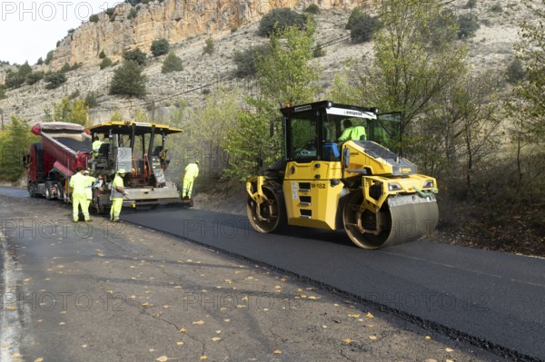 Asphalt road construction team of workers resurfacing tarmac in rural area, near Albarracin, Teruel