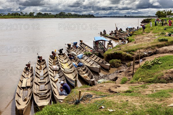 Wooden boats in a row on the banks of a river with people, longboat on a river near Rurrenabaque in