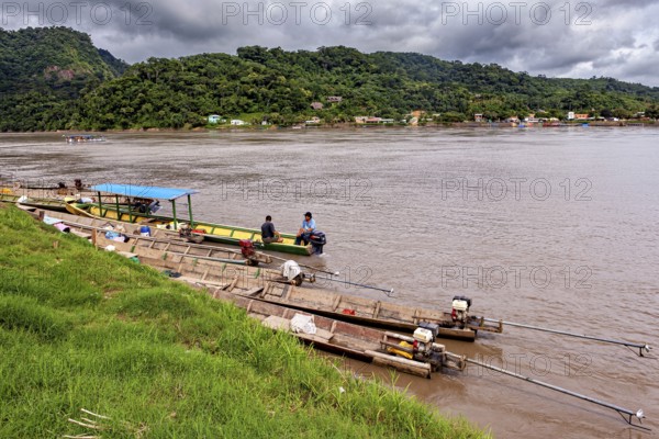 Wooden boats with motors on the banks of a river surrounded by hills, longboat on a river near