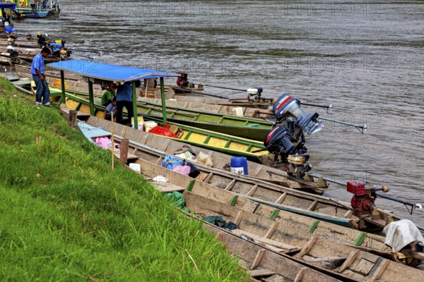 Wooden boats with motors on the banks of a river with grassy banks, longboat on a river near
