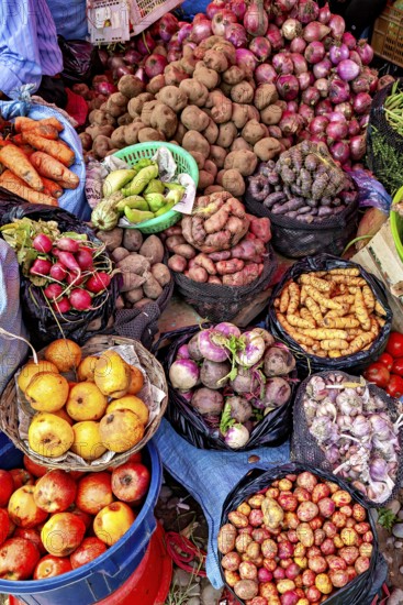 Colourful market image with a variety of fresh fruit and vegetables, including potatoes, onions and