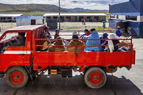 A red truck transports several people through a rural area in a quiet atmosphere, Road traffic in