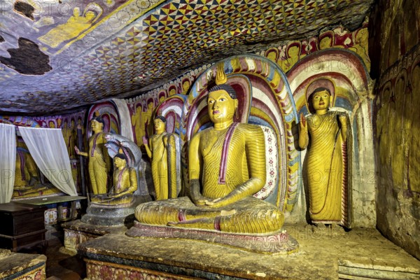 Meditative Buddha statues in a colorful cave with spiritual paintings on the walls, The cave
