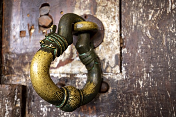 Antique brass door knocker on weathered wood, conveys a nostalgic and historic charm, door handle