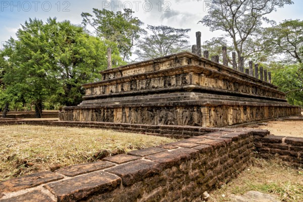 Stone plate with engravings surrounded by trees under a partly cloudy sky, The temples of