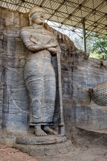 Standing rock statue with detailed texture and ancient appeal under a canopy, The Buddhas near