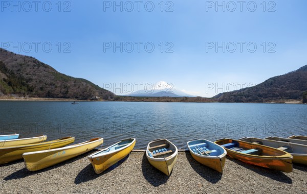 Rowing boats on shore, view across the lake to Mt Fuji volcano, Motosu Lake, Yamanashi Prefecture,