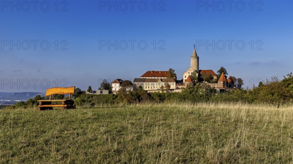 A castle on a hill with a wide meadow in the foreground and clear blue sky, The Leuchtenburg near