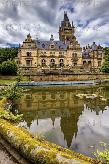Impressive castle reflected in a quiet pond, cloudy sky above, The Hummelshain hunting lodge in