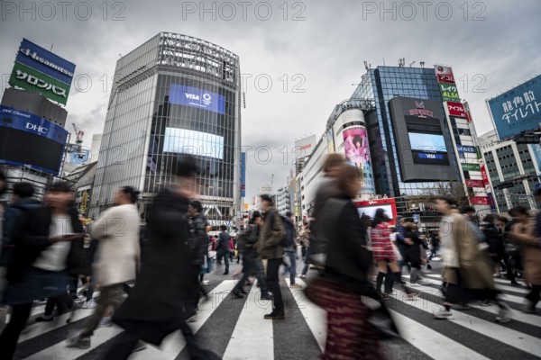 Crowd crossing zebra crossing on a large intersection, motion blur, back modern houses with