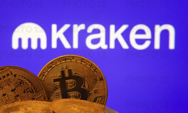 Dhaka, Bangladesh- 01 Nov 2025: Close-up of Bitcoin coins with the Kraken logo visible on a screen