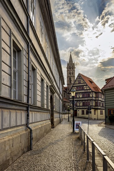 Historic city center with half-timbered houses and a church in the background under a partly cloudy