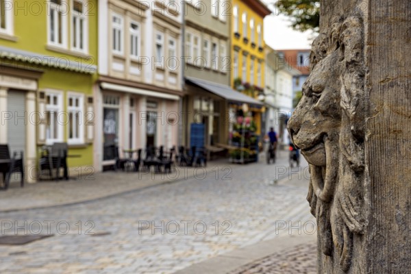Stone lion relief in front of picturesque old town street with colorful houses, lion head at the