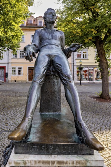 Statue of a smiling man in a square with buildings, Johann Sebastian Bach monument in the old town