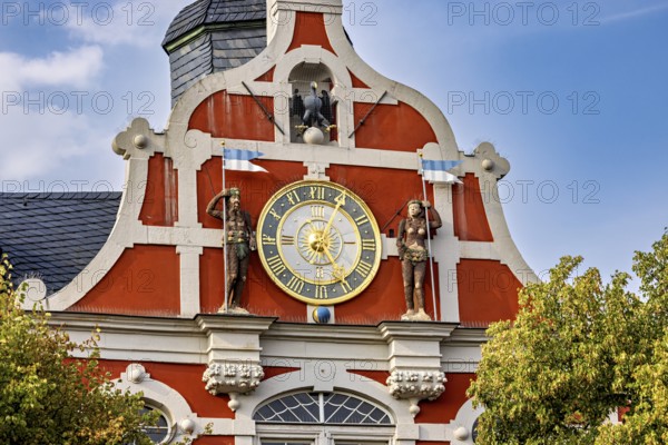 Baroque town hall façade with clock and sculptures in orange on a clear day, The old town of