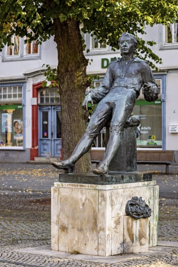 Seated bronze statue of a man under a tree in a city, Johann Sebastian Bach monument in the old