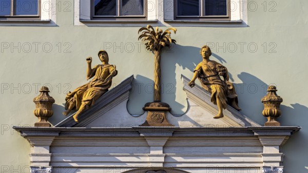 Detailed façade decoration with two statues and a decorative palm tree, statue and monument in the