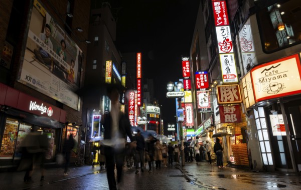 Busy pedestrian zone with many shopping centers and stores, illuminated with lots of neon signs at
