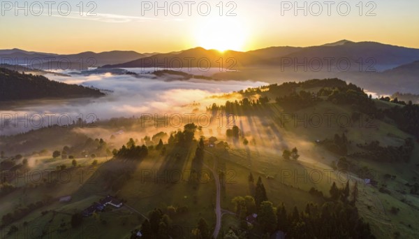 Sunrise over a fog covered village in a rural landscape, golden morning light, serene autumn