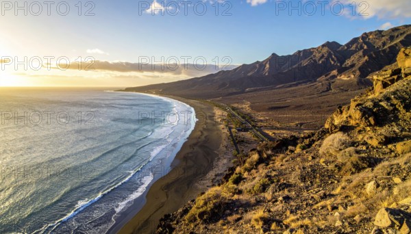Desert landscape converges with ocean along a rugged coastal area, shore break at cliffs, blue