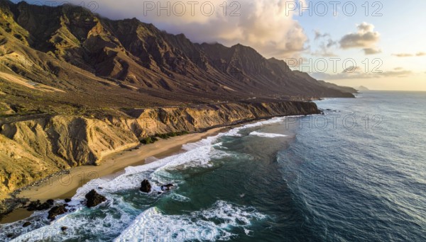 Desert landscape converges with ocean along a rugged coastal area, shore break at cliffs, blue