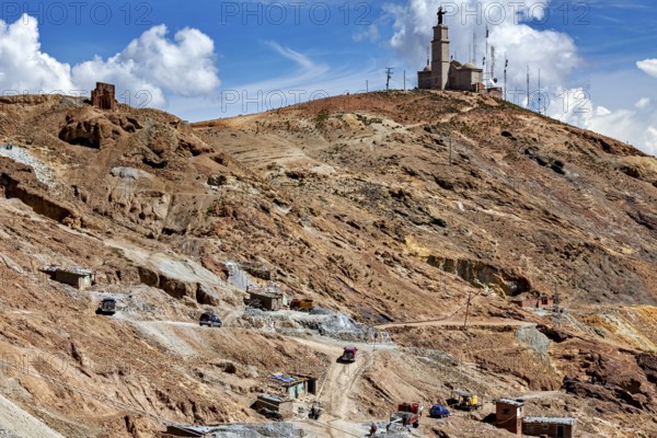 Statue on a hill with some huts and a dry, dusty mountain behind, The silver mines of Potosi