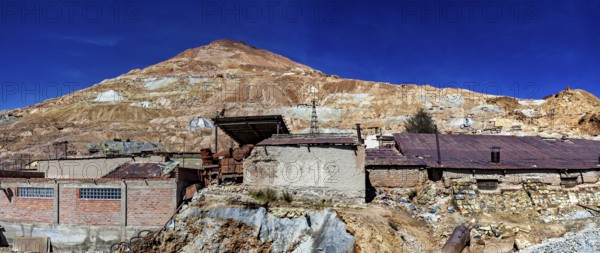 Abandoned buildings on a mountainside with a rocky landscape and a clear blue sky, The silver mines