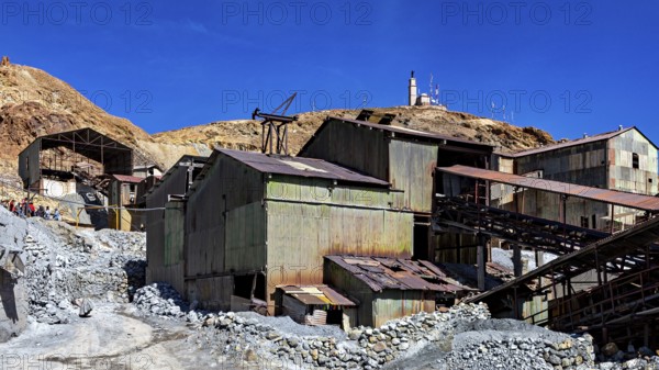 Weathered metal industrial buildings on a mountainside under a clear blue sky, The silver mines of