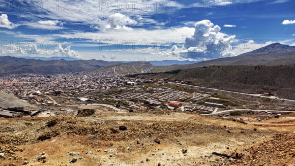 Large cityscape between hills under a dramatically cloudy sky with a wide view, view from Silver